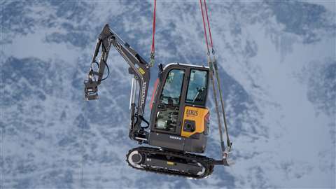 The Volvo ECR25 electric compact excavator hovers precariously above the Swiss Alps